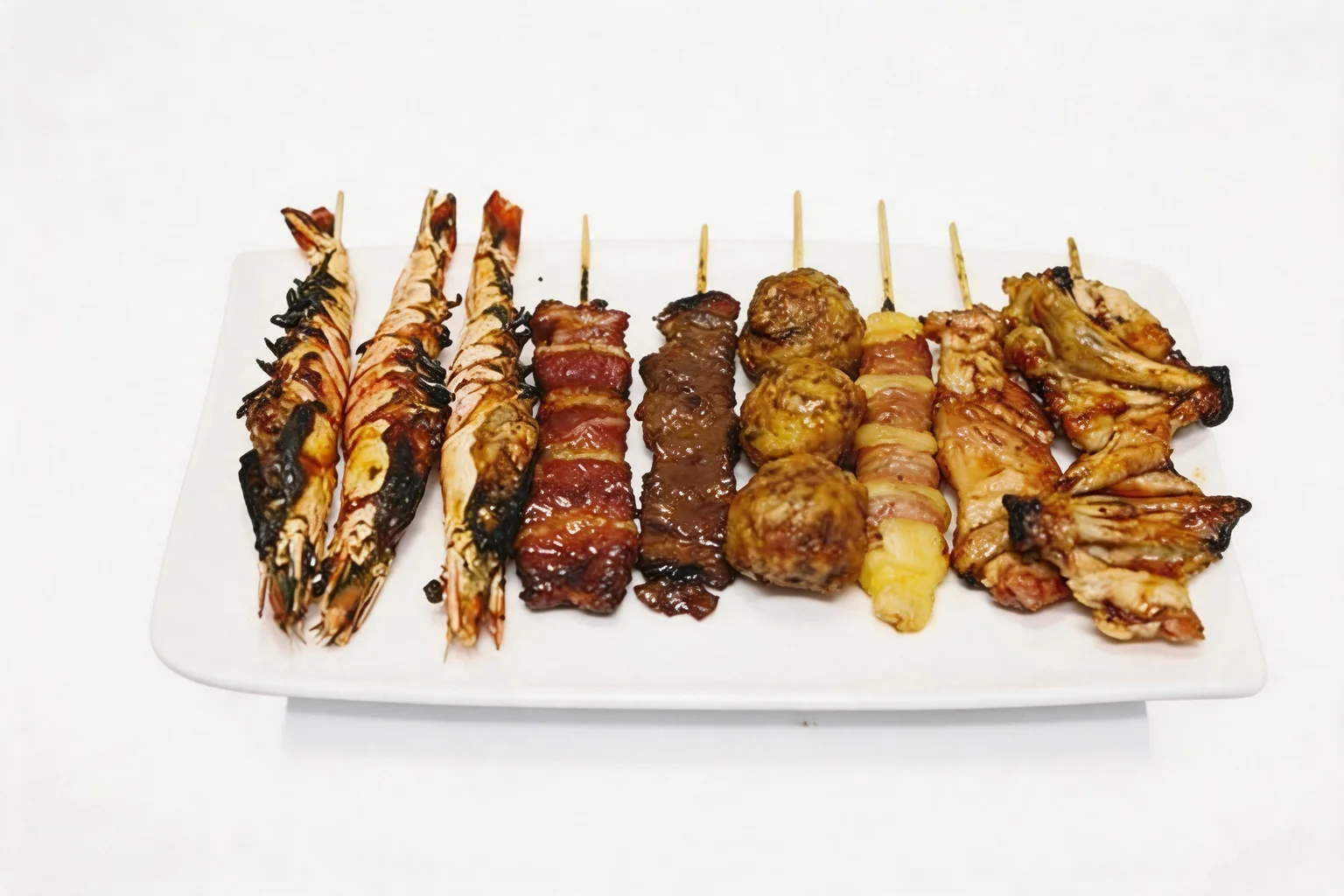 Nine assorted grilled skewers — shrimp, beef, meatballs, cheese and chicken — on a white plate